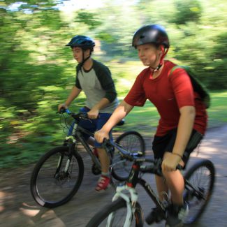 Campers riding mountain bikes in the forest.
